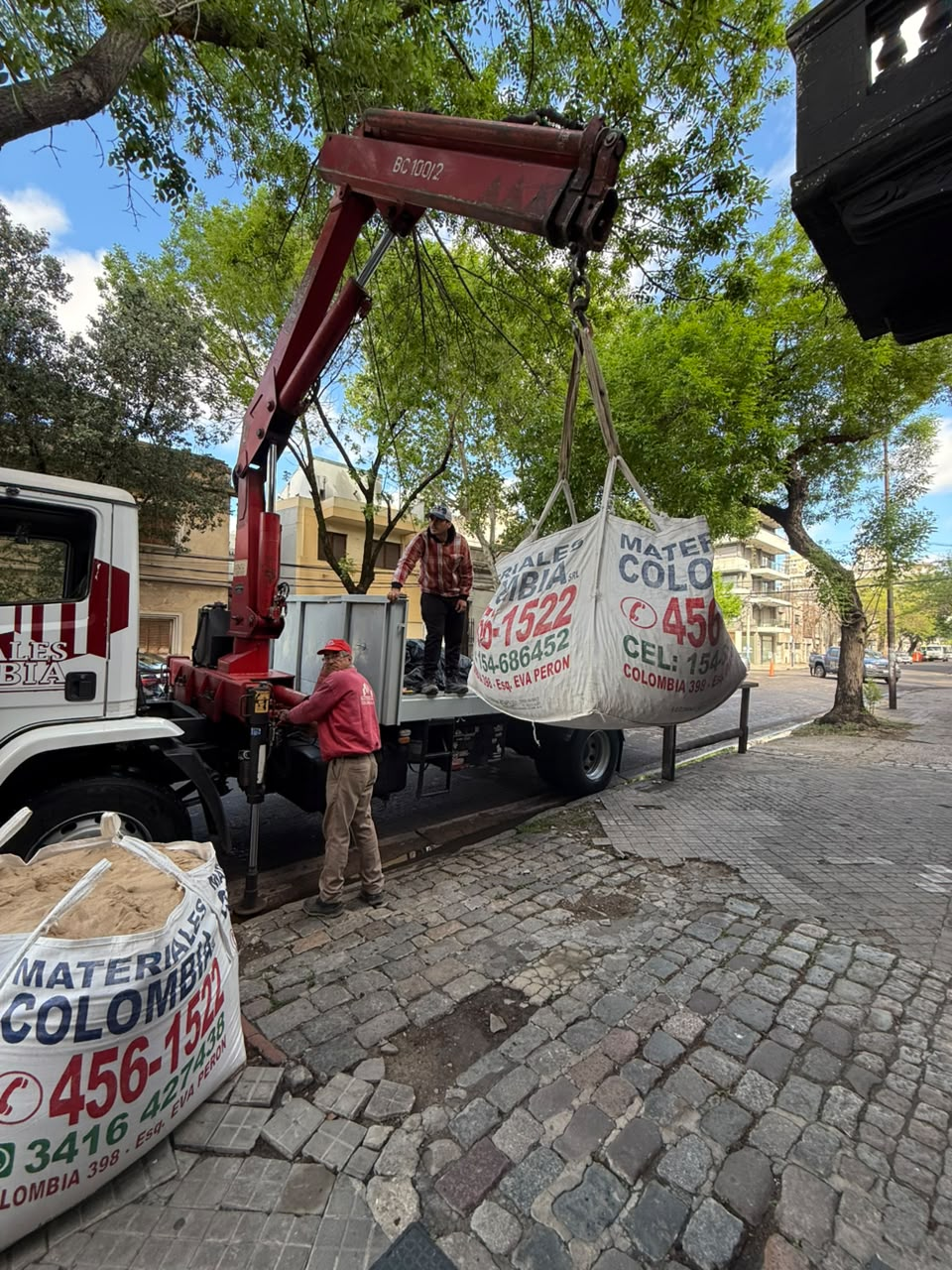 Camión de Materiales Colombia descargando un bolsón con grúa